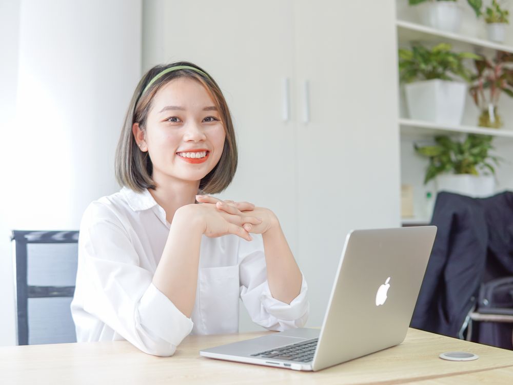 Jovem sorrindo à mesa com o notebook